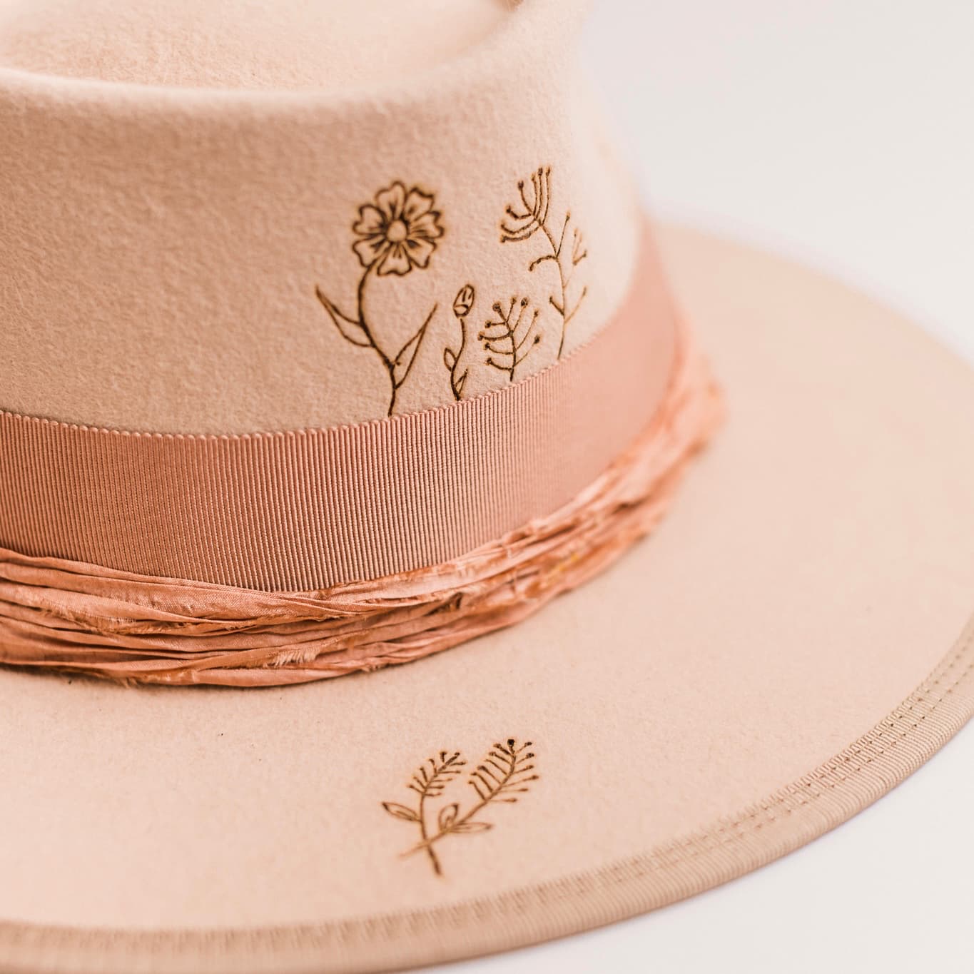Close up detail of the Miley felt hat showing burnt branded botanical motif on the brim.
