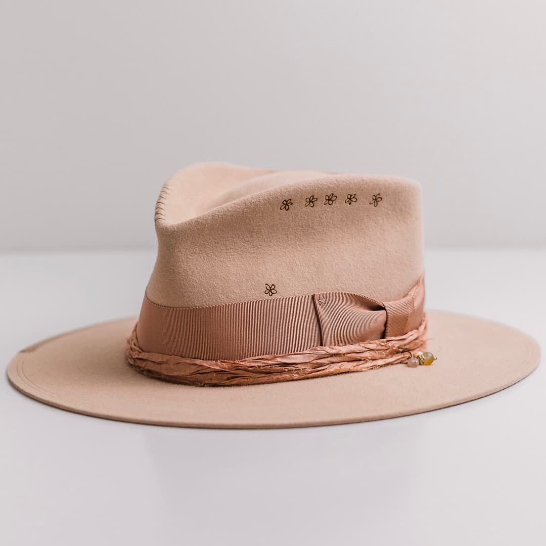 Front left angle of the sand felt hat Miley by PHYLLi Designs with dirty rose grosgrain band and sari silk trimming.