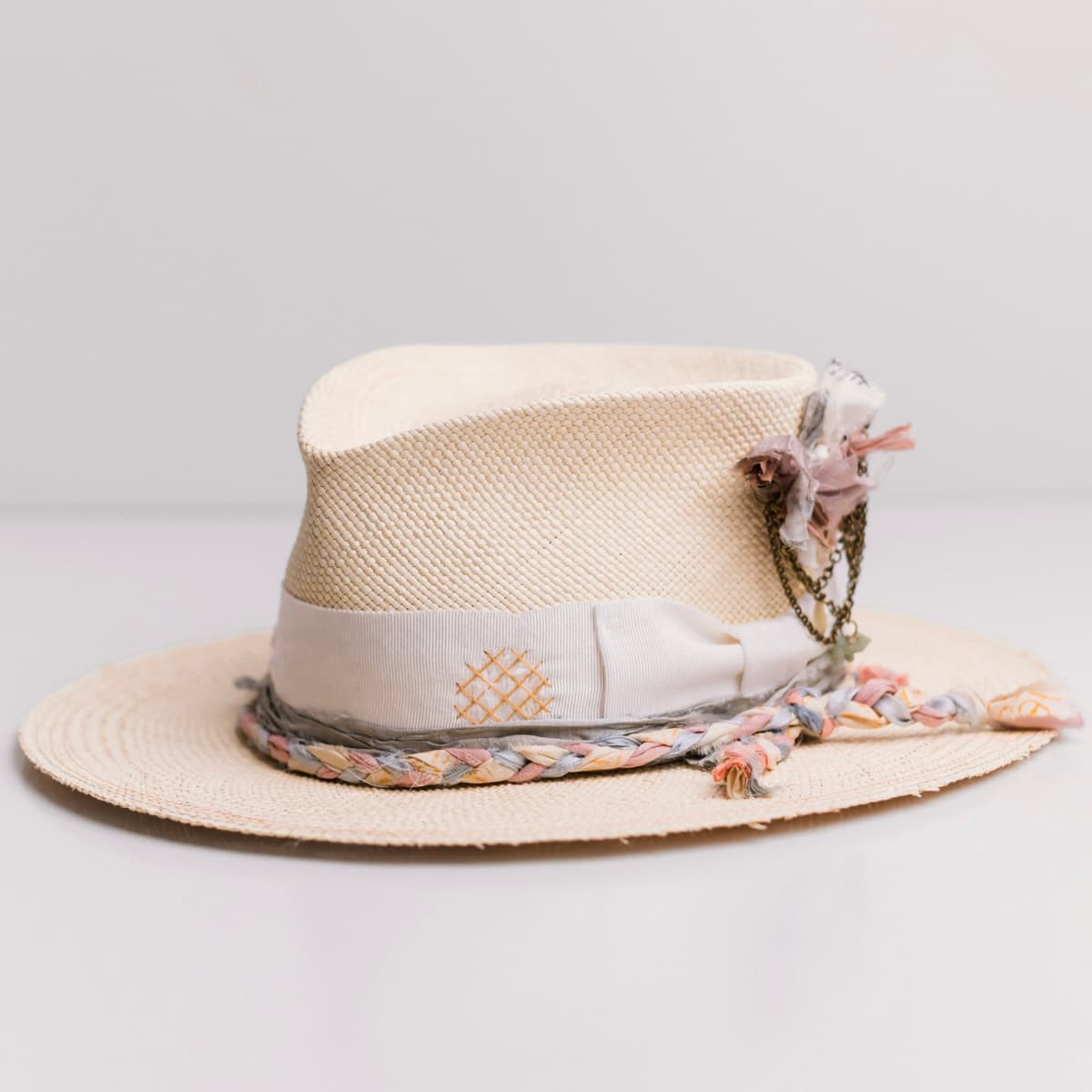 Front left angle of the My Magical Natural Panama hat by PHYLLi Designs with distressed ivory Japanese grosgrain band and plaited sari silk trim in storm, floss and sunshine.