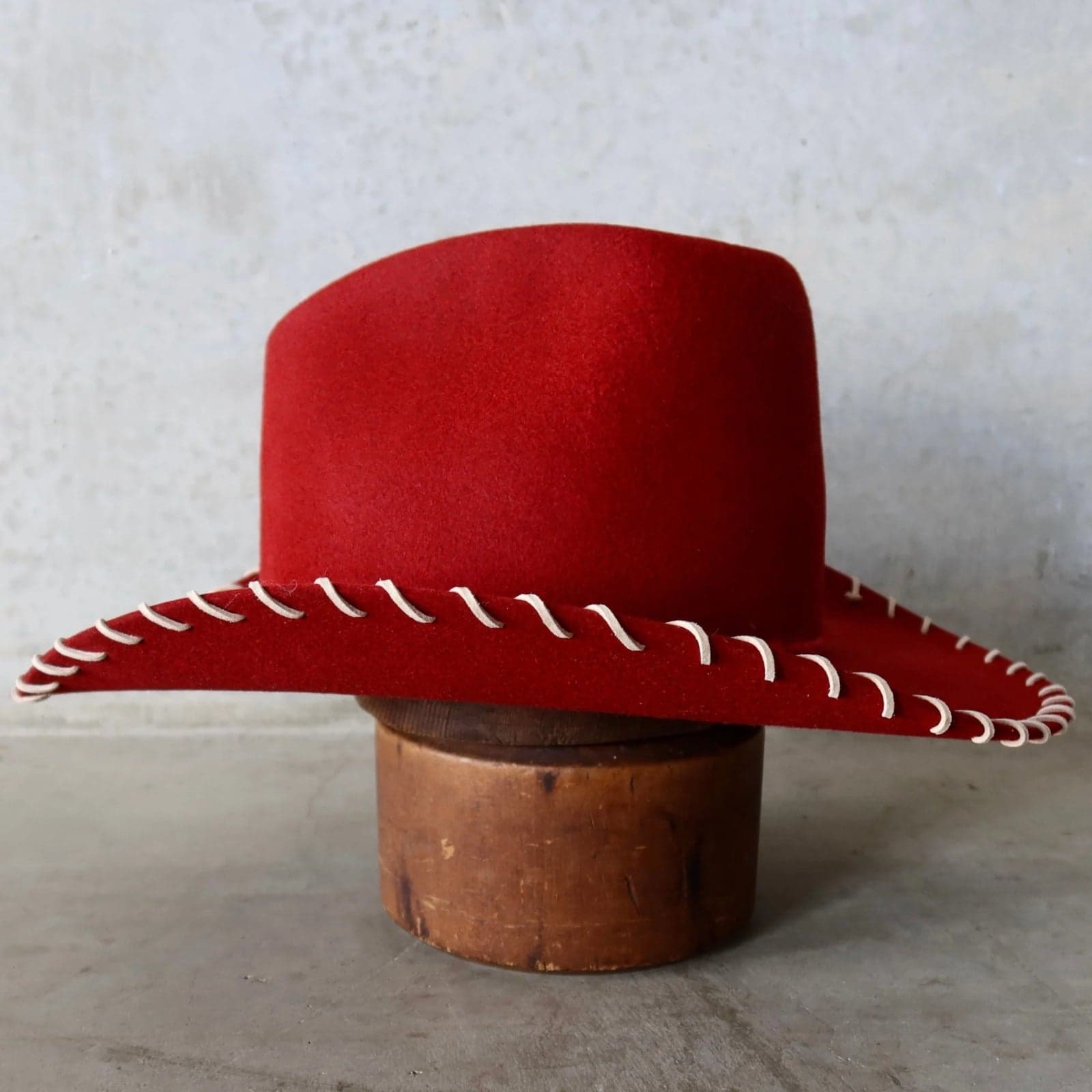 Left side view of the spiced cherry felt cowboy hat Nevada by PHYLLi Designs with nude suede brim lacing.