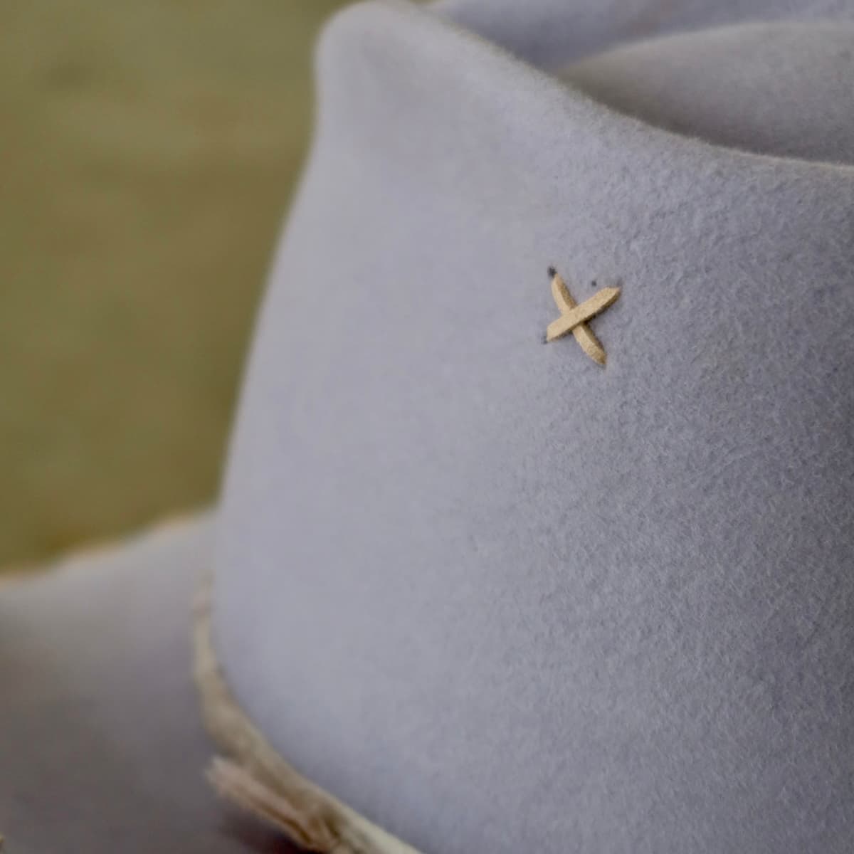 Close up detail of the Nevada cowboy hat showing hand-stitched suede cross detail on the lilac felt crown.