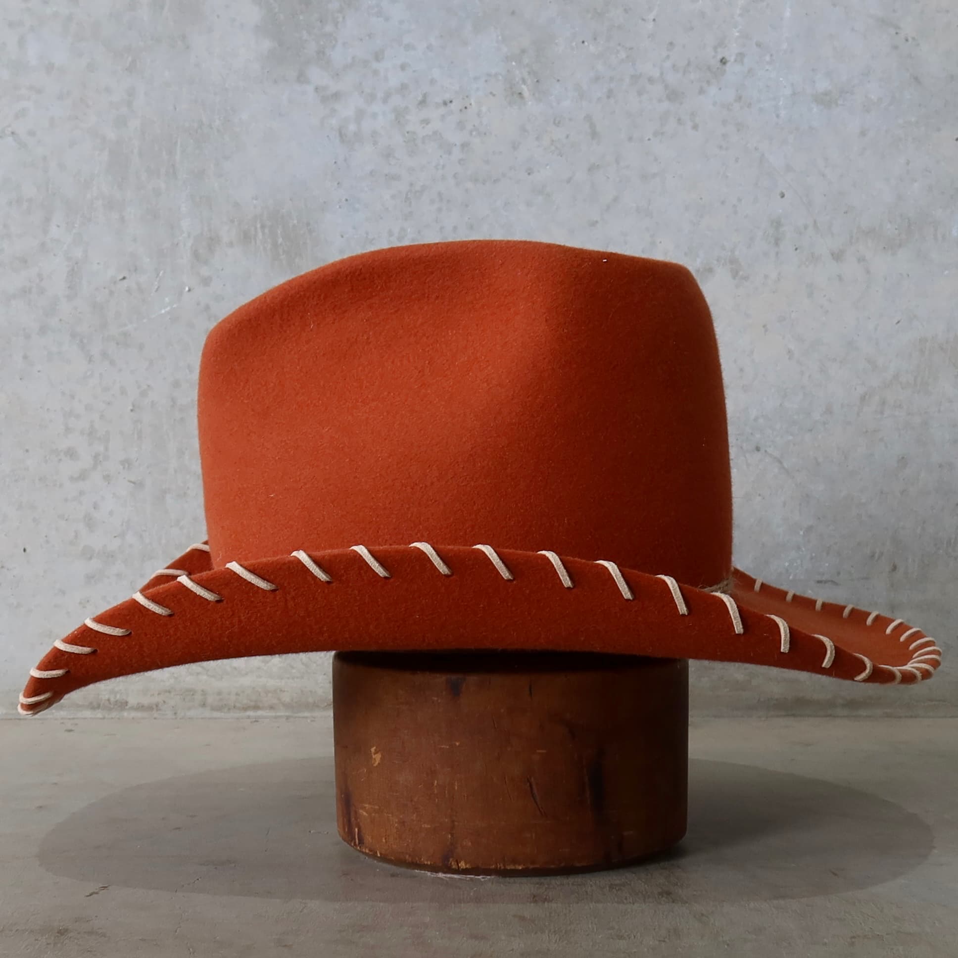 Left side view of the spiced pumpkin cowboy hat Nevada by PHYLLi Designs with three twine wraps and nude suede brim lacing.