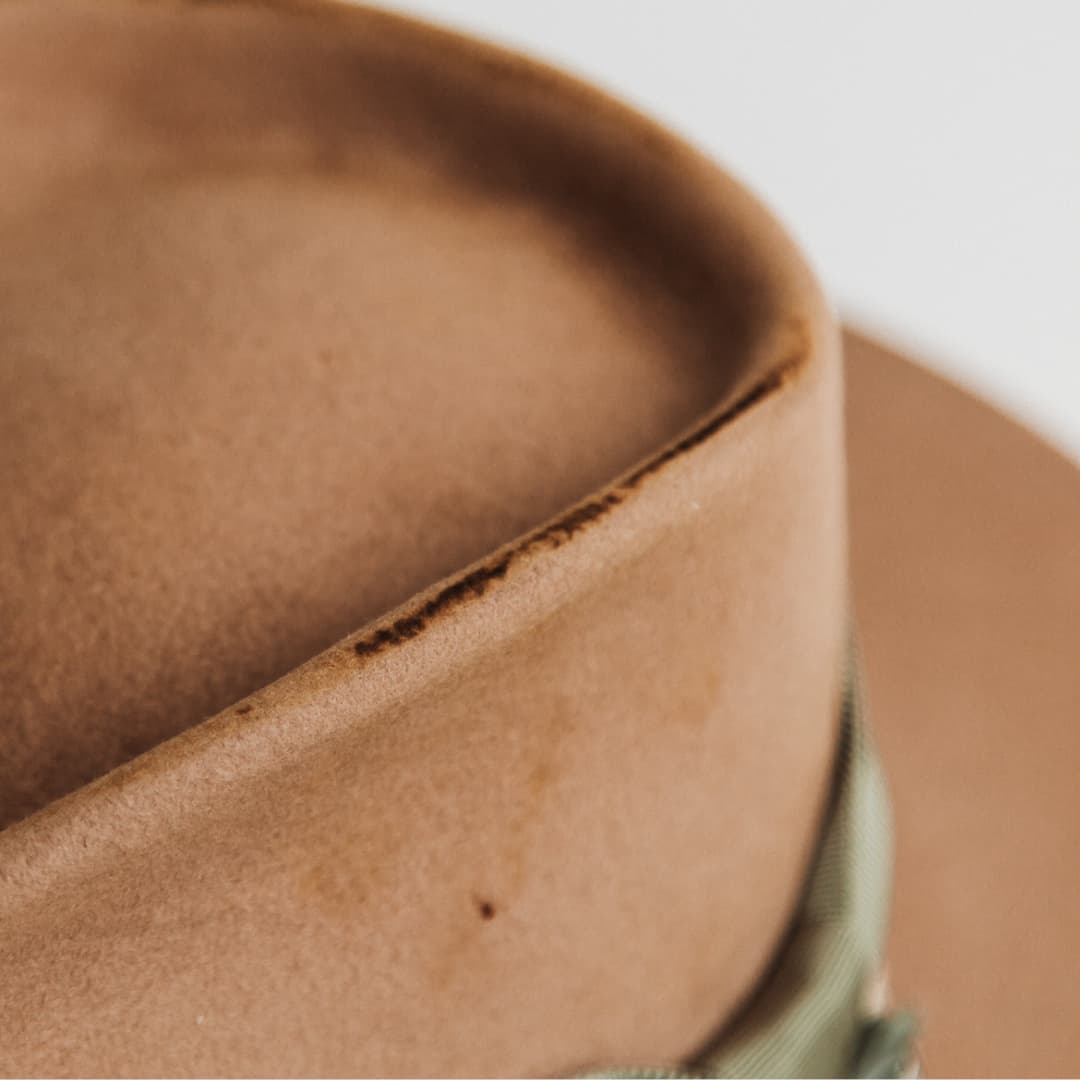 Close up detail of the Nim camel distressed felt hat by PHYLLi Designs showing hand-distressed crown edge on premium rabbit felt.