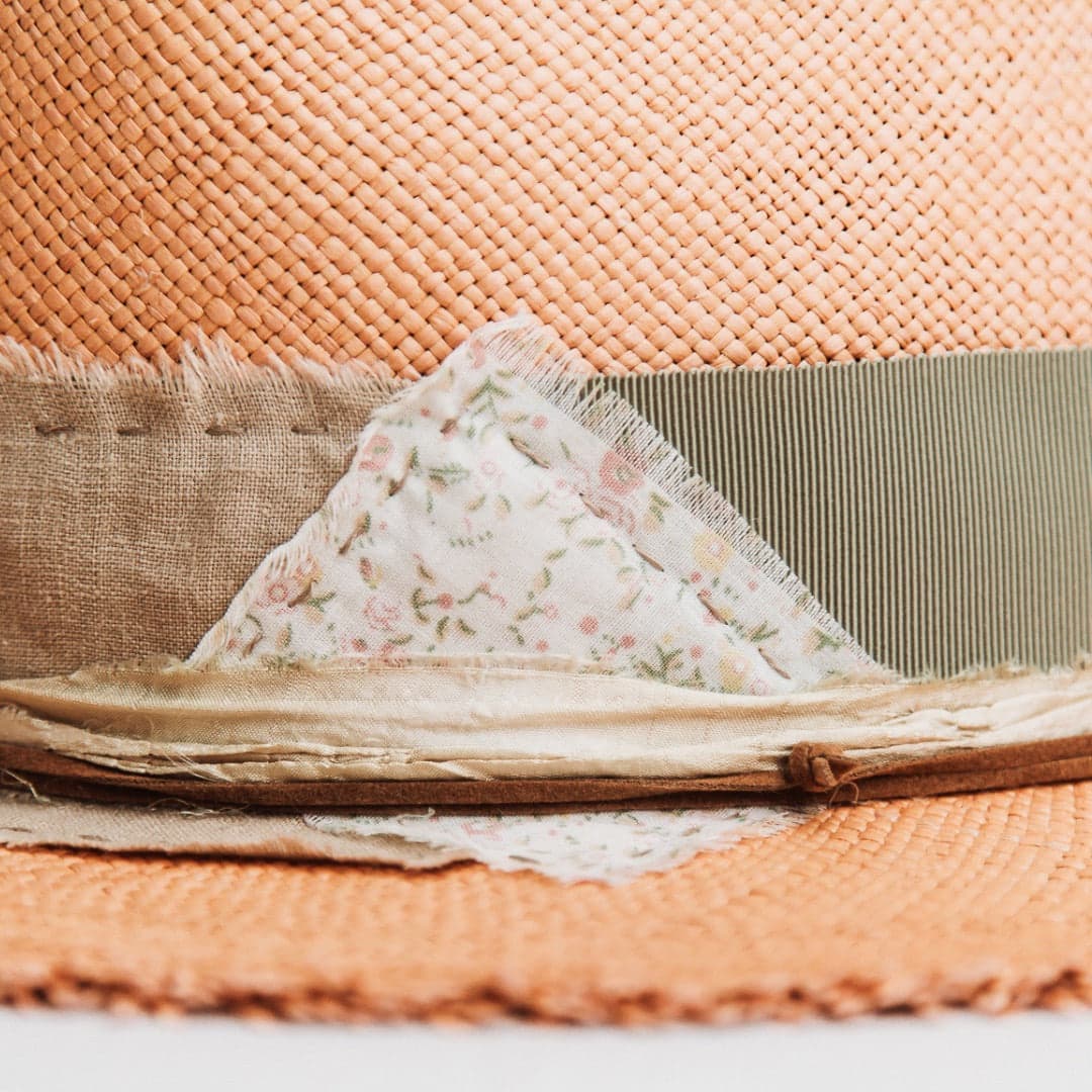 Close up detail of the Nim Panama hat showing floral and linen patches with tan suede string.