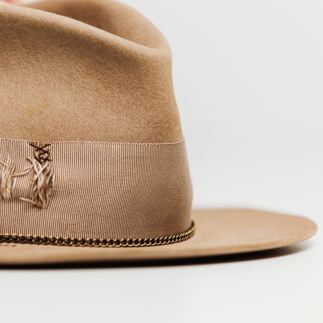 Close up detail of the Normie felt hat showing chocolate darned patches stitched into the grosgrain band.