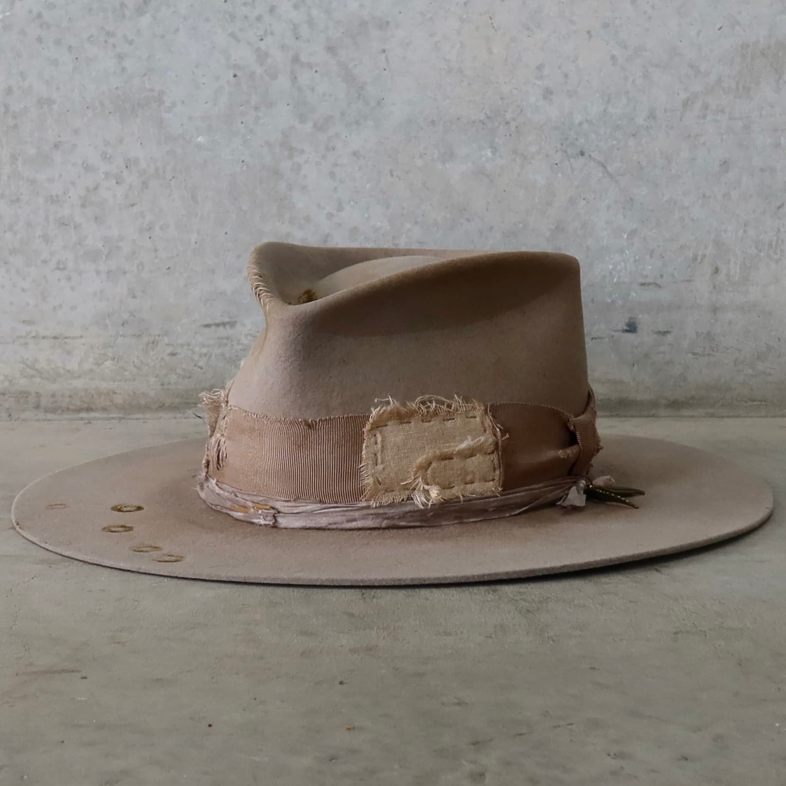 Front left angle of the Sahara felt hat Oakley Limited Edition by PHYLLi Designs with distressed taupe grosgrain band and layered linen and cotton patches.