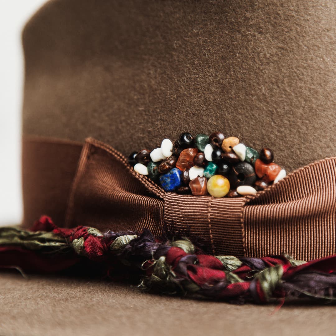 Close up detail of the Olive Enchanted felt hat showing chocolate Japanese grosgrain bow band with bead cluster detail.