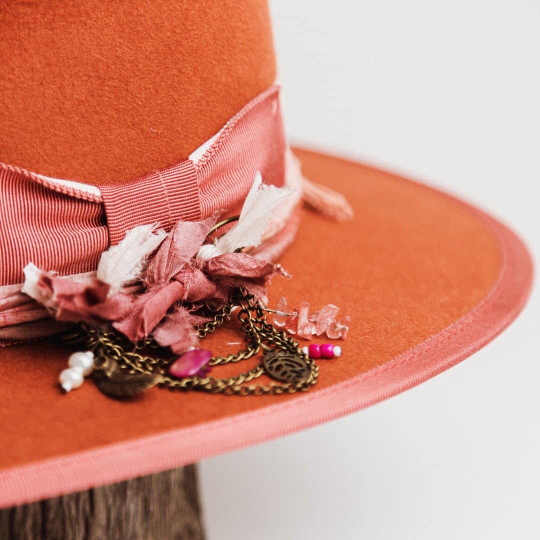 Close up detail of the Pamela felt hat showing watermelon grosgrain bow and bronze chunky hat pin with charms and tassel.