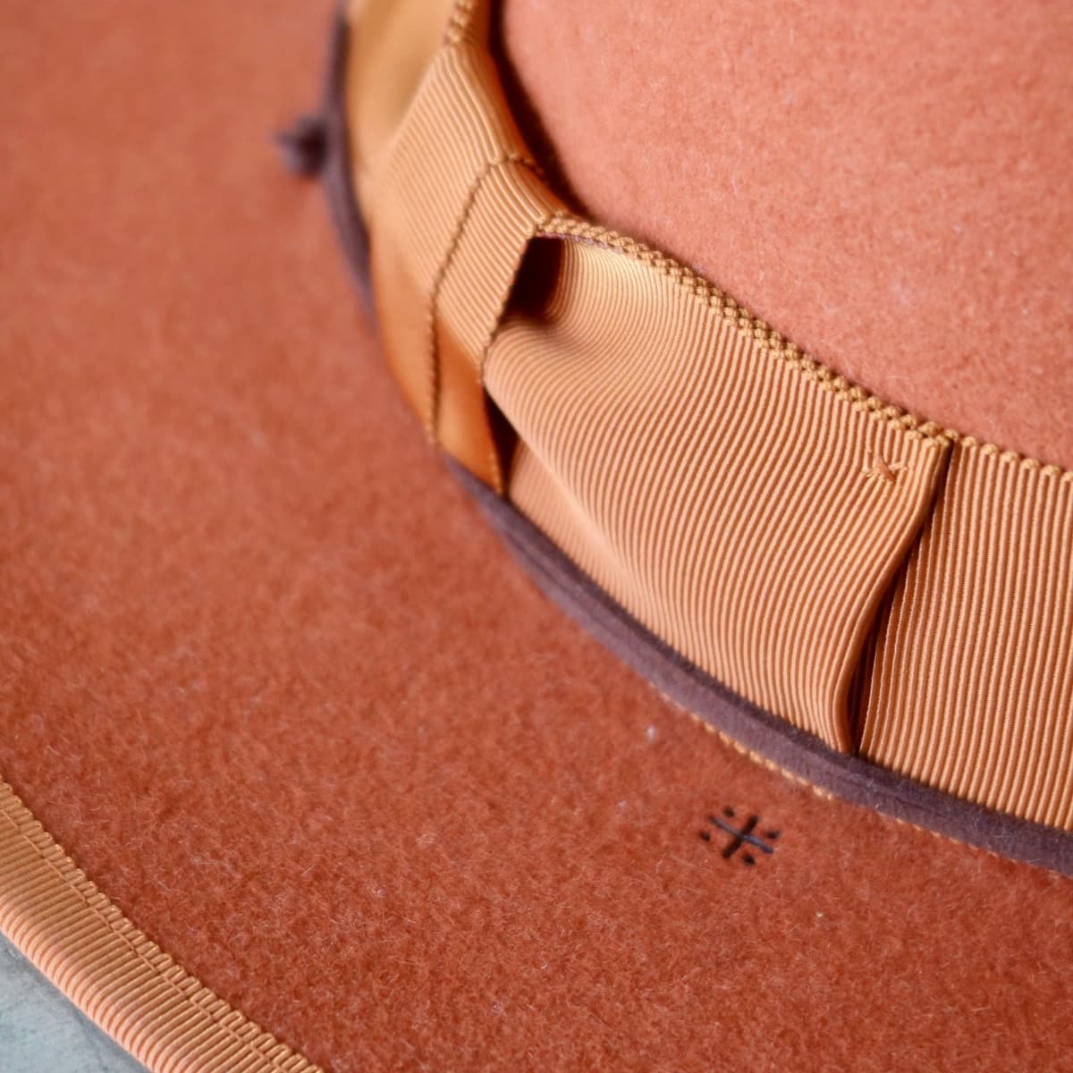 Close up detail of the Patrick felt hat showing rust grosgrain band with chocolate suede string wrap.