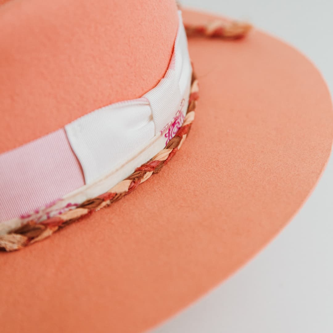 Close up detail of The Peach felt hat by PHYLLi Designs showing plaited sari silk trim in pink, bronze and ivory and ivory bow.