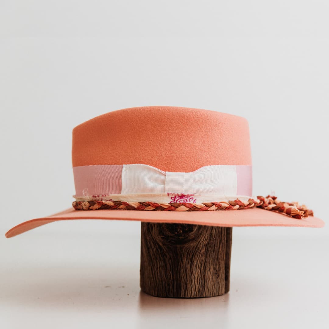 Left side view of The Peach felt hat by PHYLLi Designs with plaited sari silk trim and ivory and pink sari silk trimming.