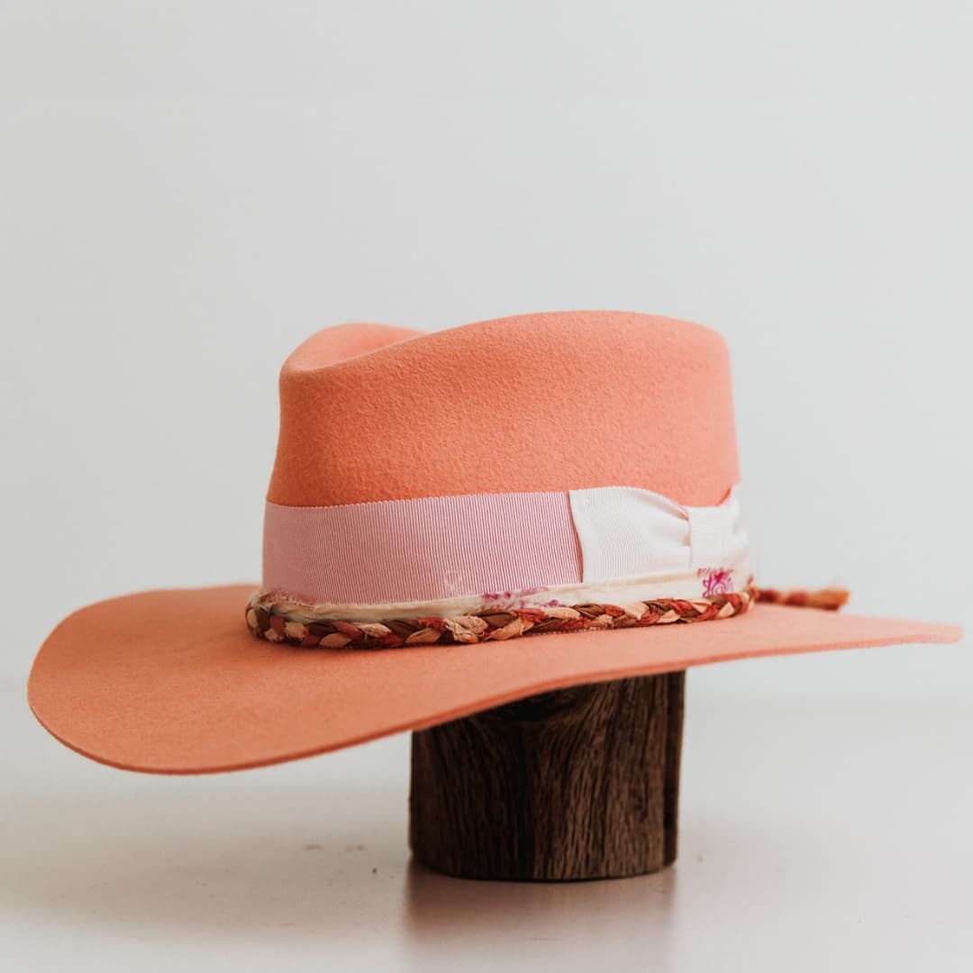 Front left angle of The Peach felt hat by PHYLLi Designs with floss pink grosgrain band, ivory bow and plaited sari silk detailing.