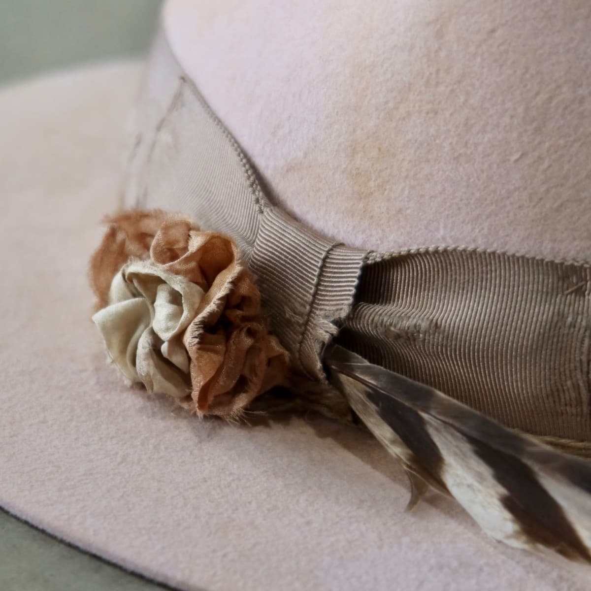 Close up detail of the Pink Bloom felt hat showing sari silk lapel bloom with pearl centre and feather detail.