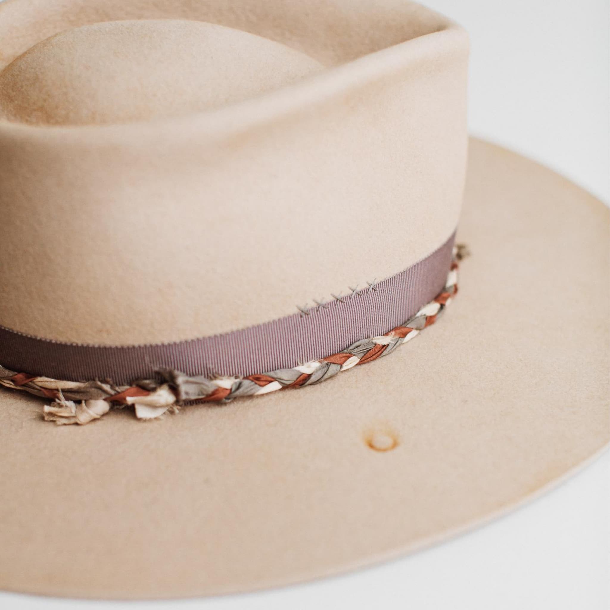 Close-up detail of Plum Twist beige distressed felt hat by PHYLLi Designs showing vintage mauve grosgrain bow band and plaited sari silk trim in mauve, ivory and plum.