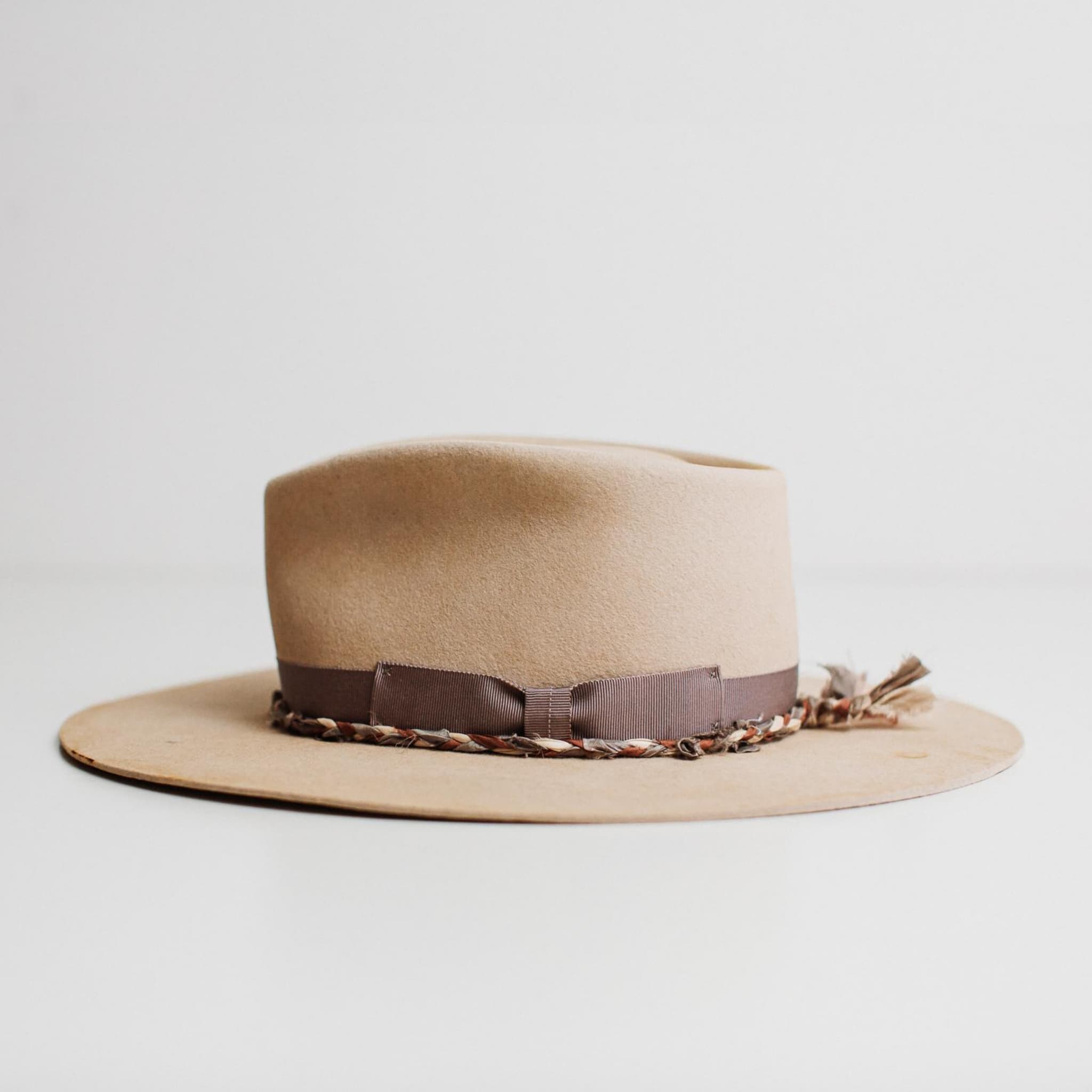Left side view of Plum Twist beige distressed felt hat by PHYLLi Designs showing plaited sari silk trim and hand-stitched crosses in mauve.