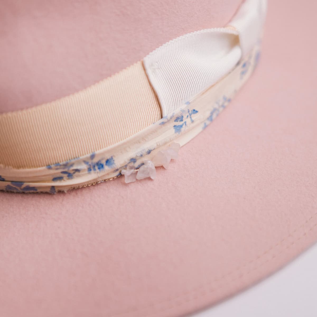 Close up detail of the Posie felt hat showing rose quartz crystal cluster set into the sari silk trim.