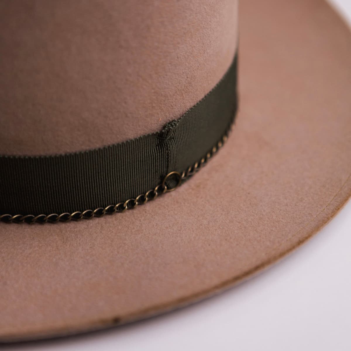 Close up detail of the Reagent felt hat showing distressed Sahara felt crown with artichoke grosgrain ribbon band and bronze crown chain.