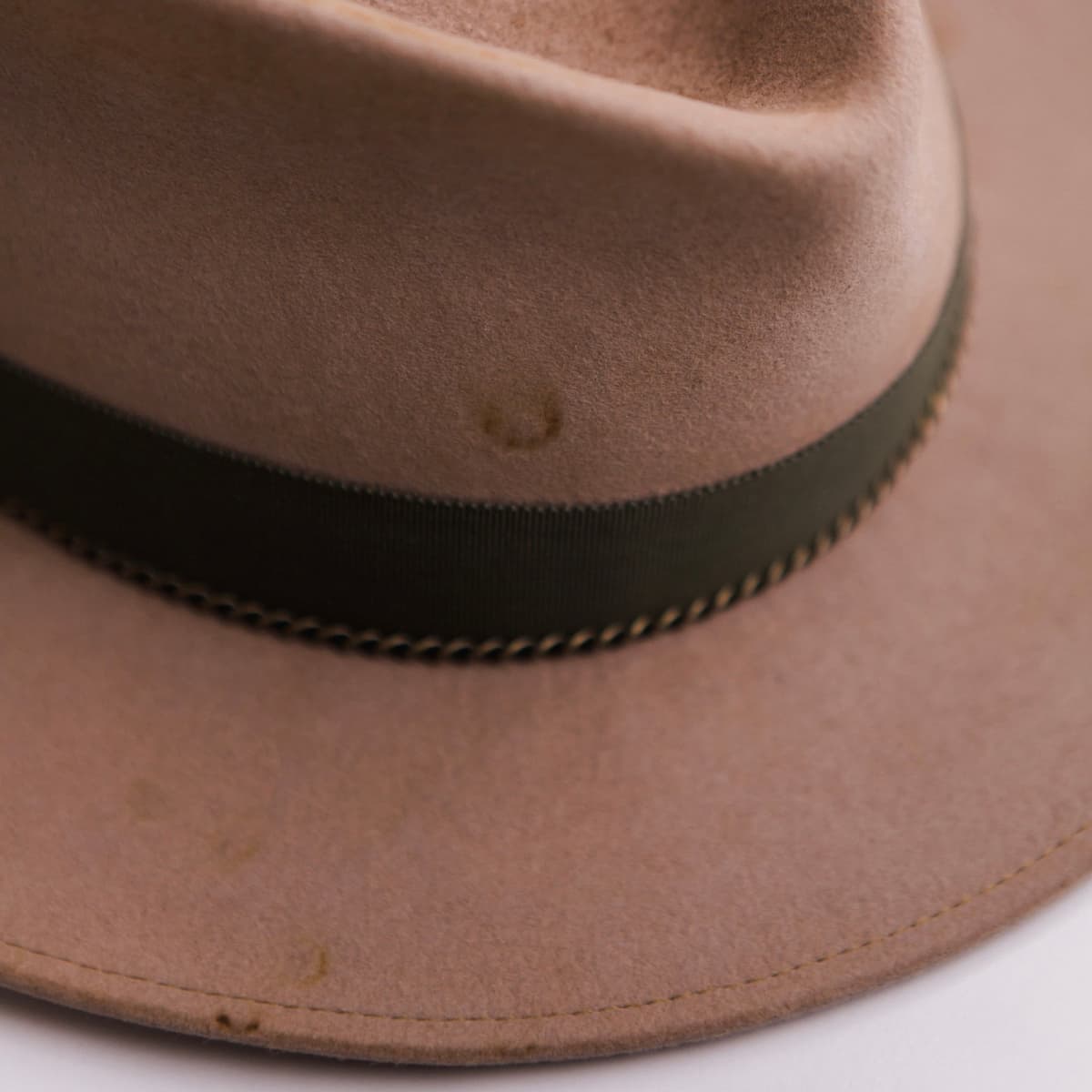 Close up detail of the Reagent felt hat showing bronze crown chain and artichoke grosgrain ribbon band.