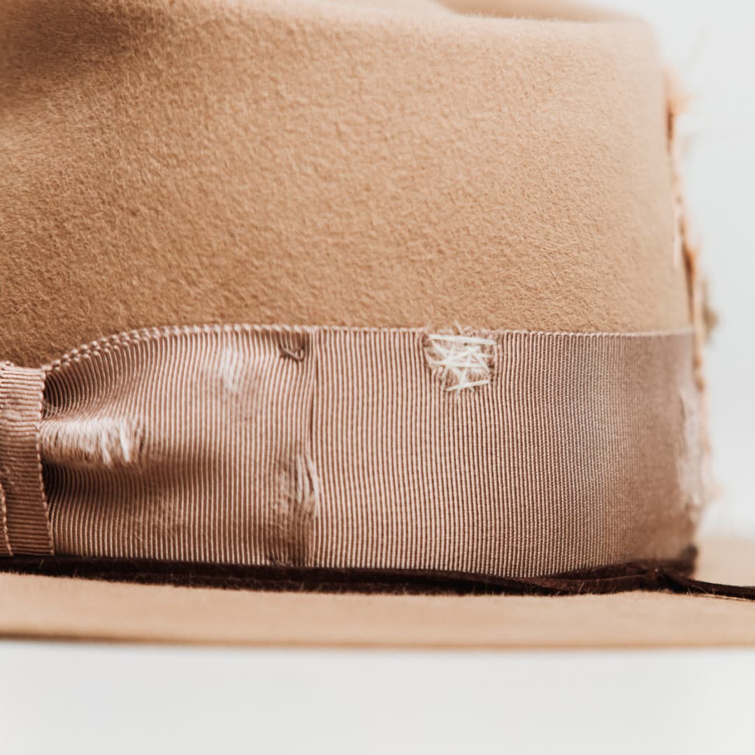 Close up detail of the Reiko felt hat showing distressed plaster grosgrain bow and stitching detail.