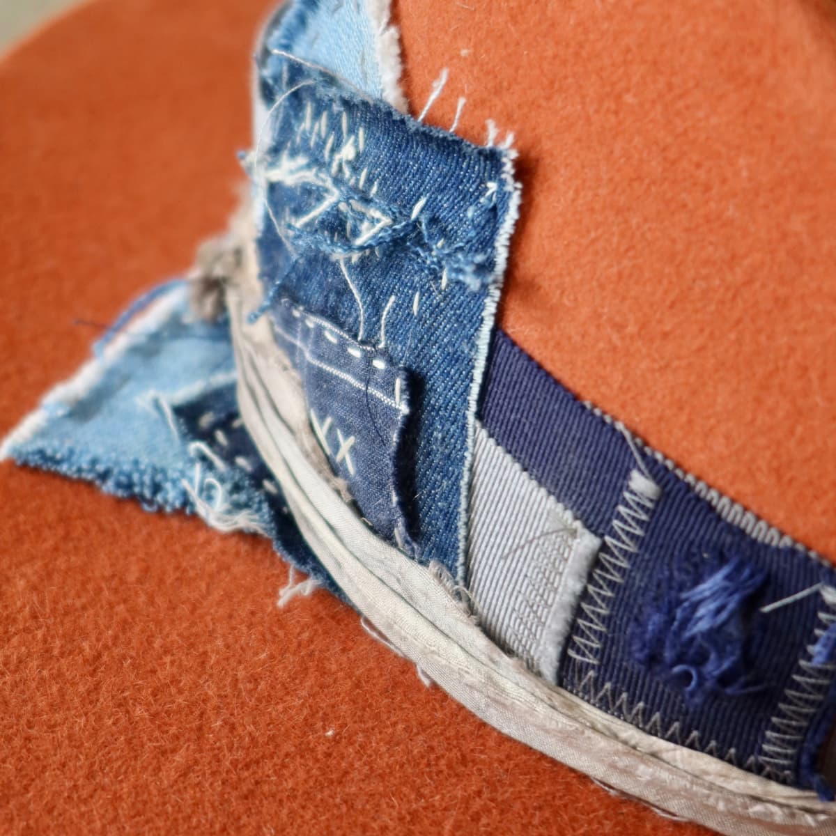 Close up detail of the Road Less Travelled felt hat showing worn denim patch with visible hand stitching.