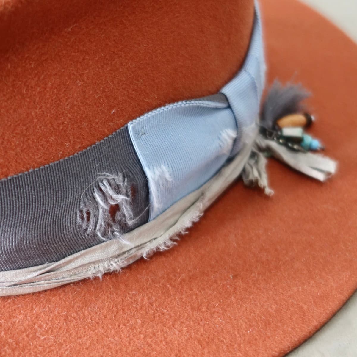 Close up detail of the Road Less Travelled felt hat showing distressed cornflower grosgrain band and frayed trim.