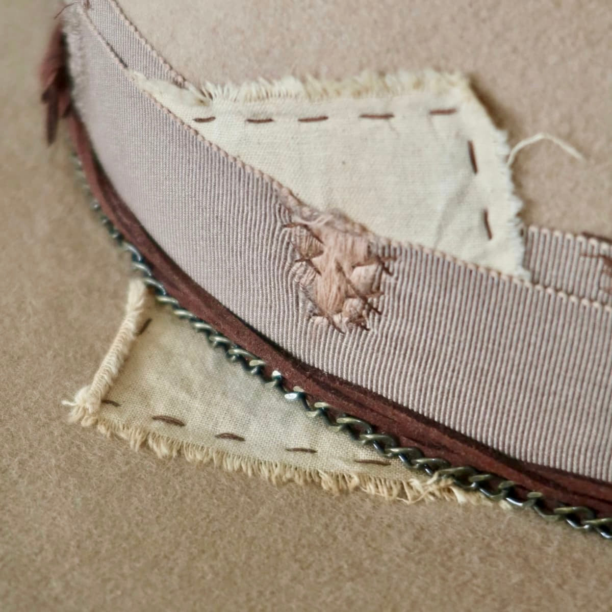 Close up of Roadie felt hat by PHYLLi Designs featuring worn linen patch and distressed grosgrain band.