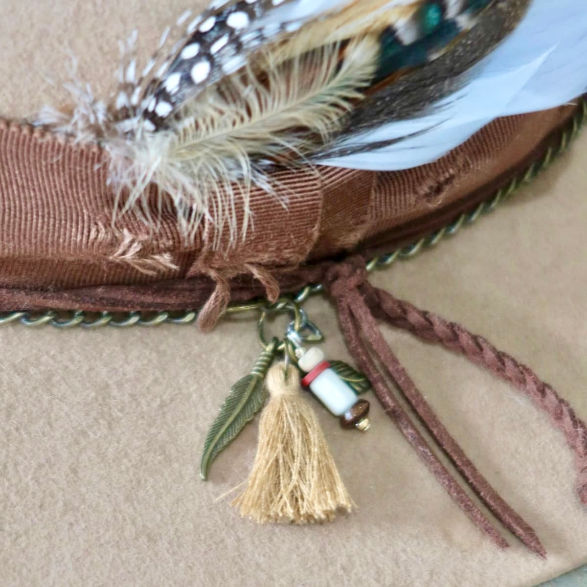 Close up of Roadie felt hat by PHYLLi Designs featuring charm cluster with tassel, bronze pendant charms and plaited suede string.