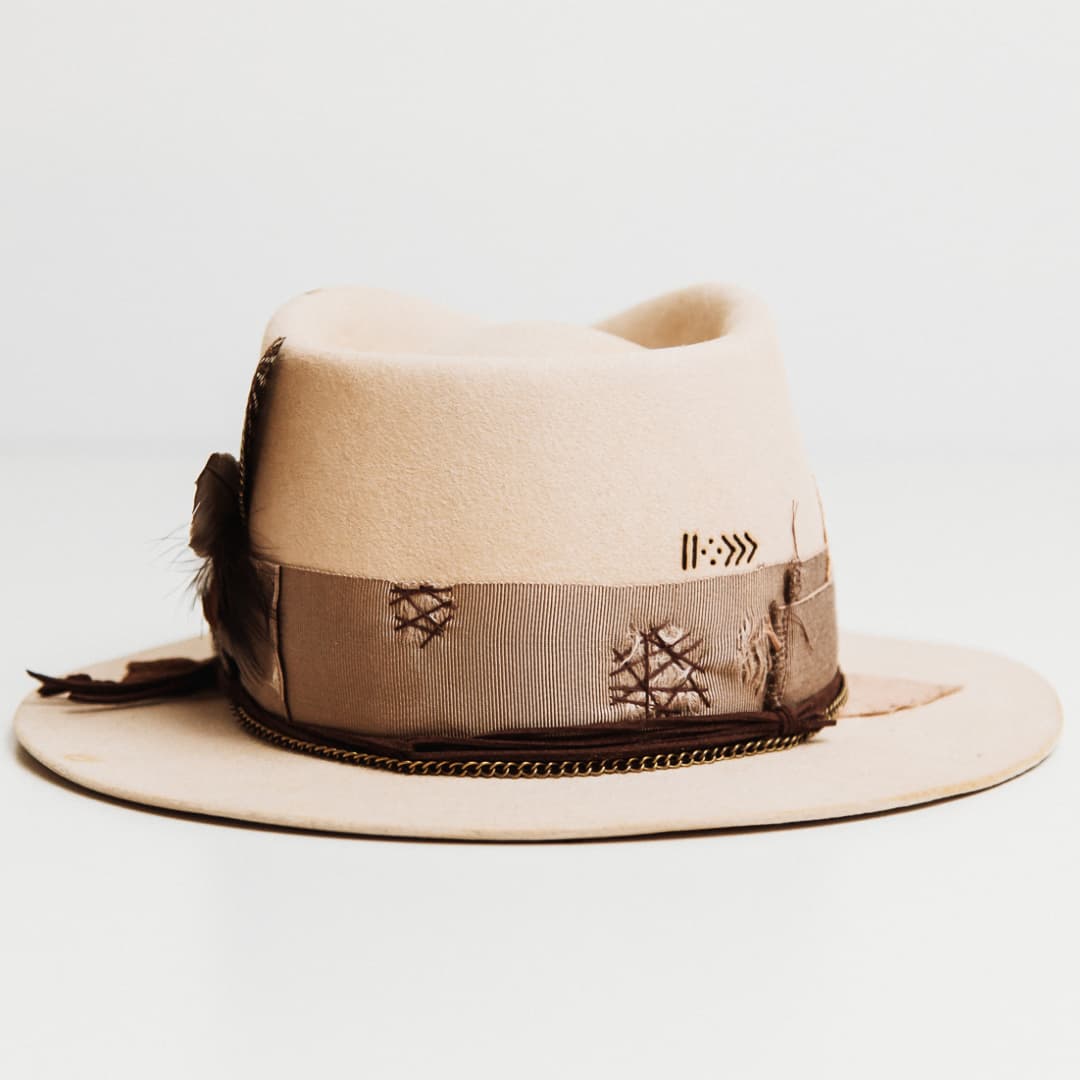 Back view of the Roadie beige felt hat by PHYLLi Designs featuring distressed grosgrain band with darned patches and suede string wraps.