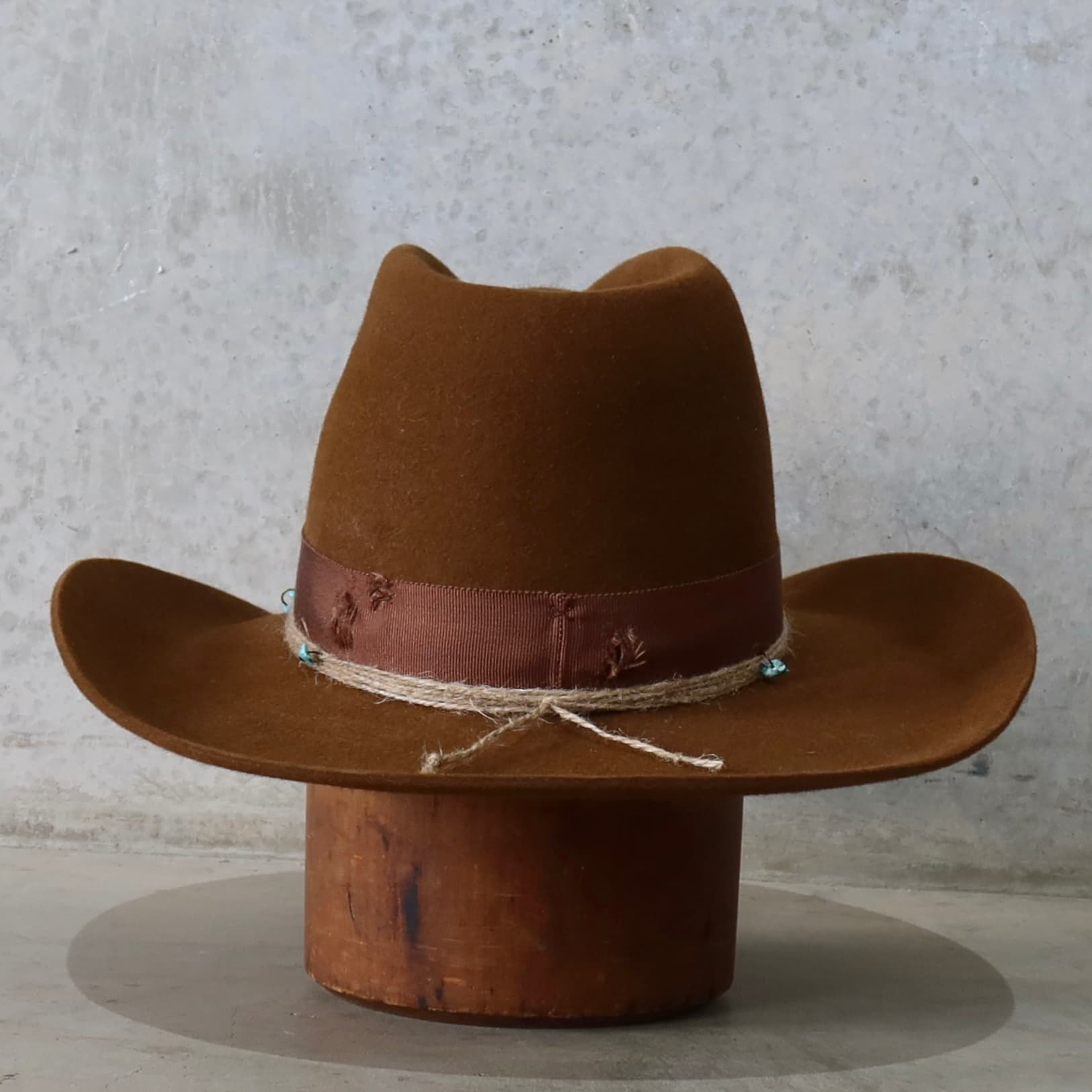 Back view of the caramel cowboy hat Rue by PHYLLi Designs featuring three twine wraps finished with turquoise beading.