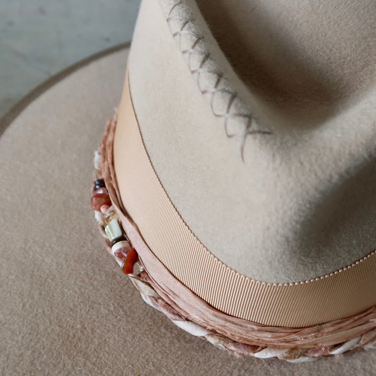 Close up detail of the Sandstone Limited Edition felt hat showing hand-stitched crosses in taupe on the sand felt crown.