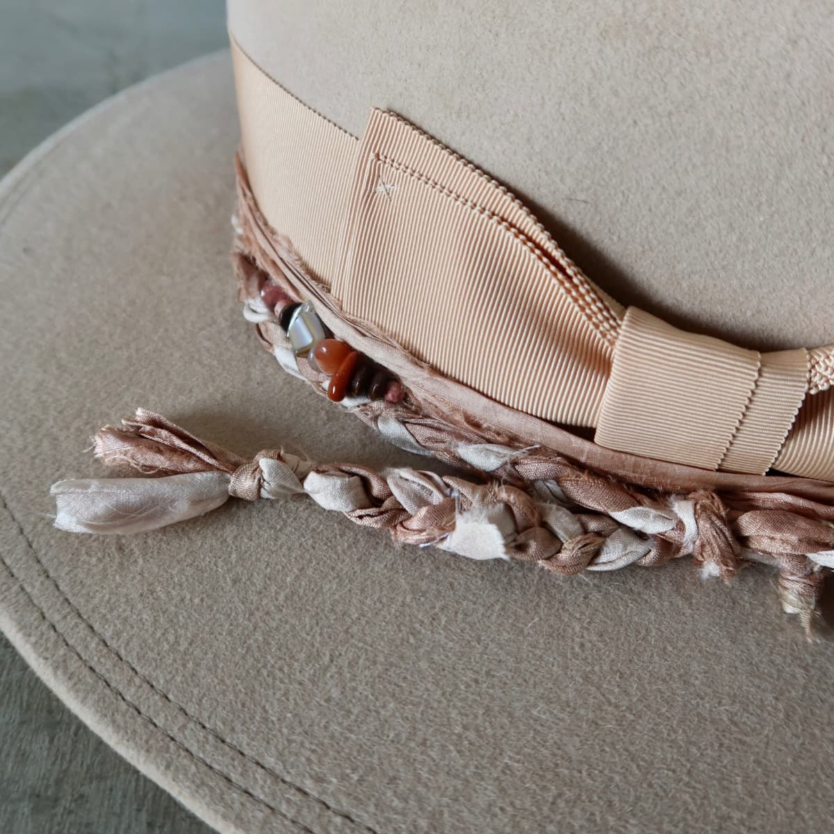 Close up detail of the Sandstone Limited Edition felt hat showing plaited sari silk trimming with assorted beading.