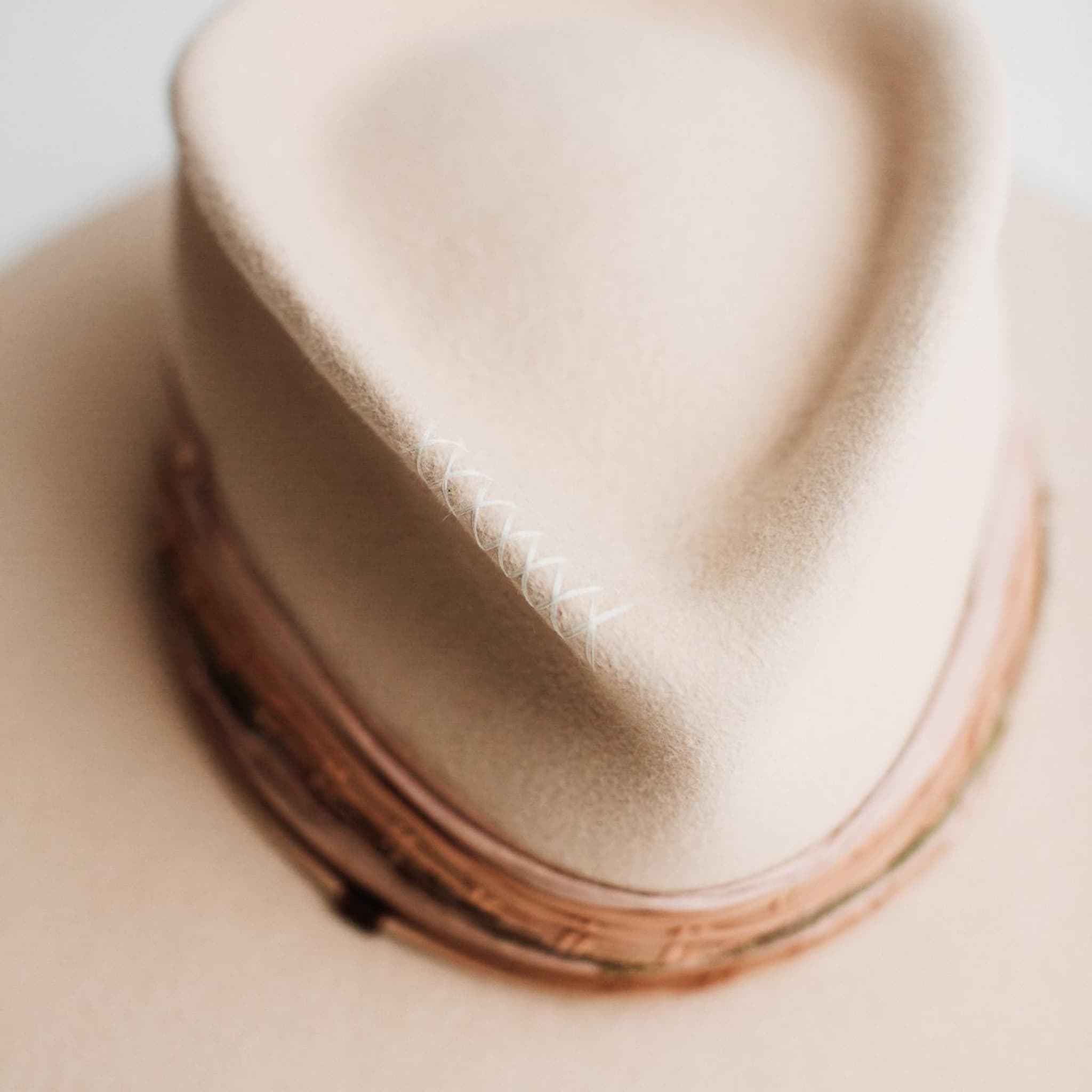 Close-up detail of Santa Fe Summer beige felt hat by PHYLLi Designs showing sari silk trimming and hand-stitched crosses.