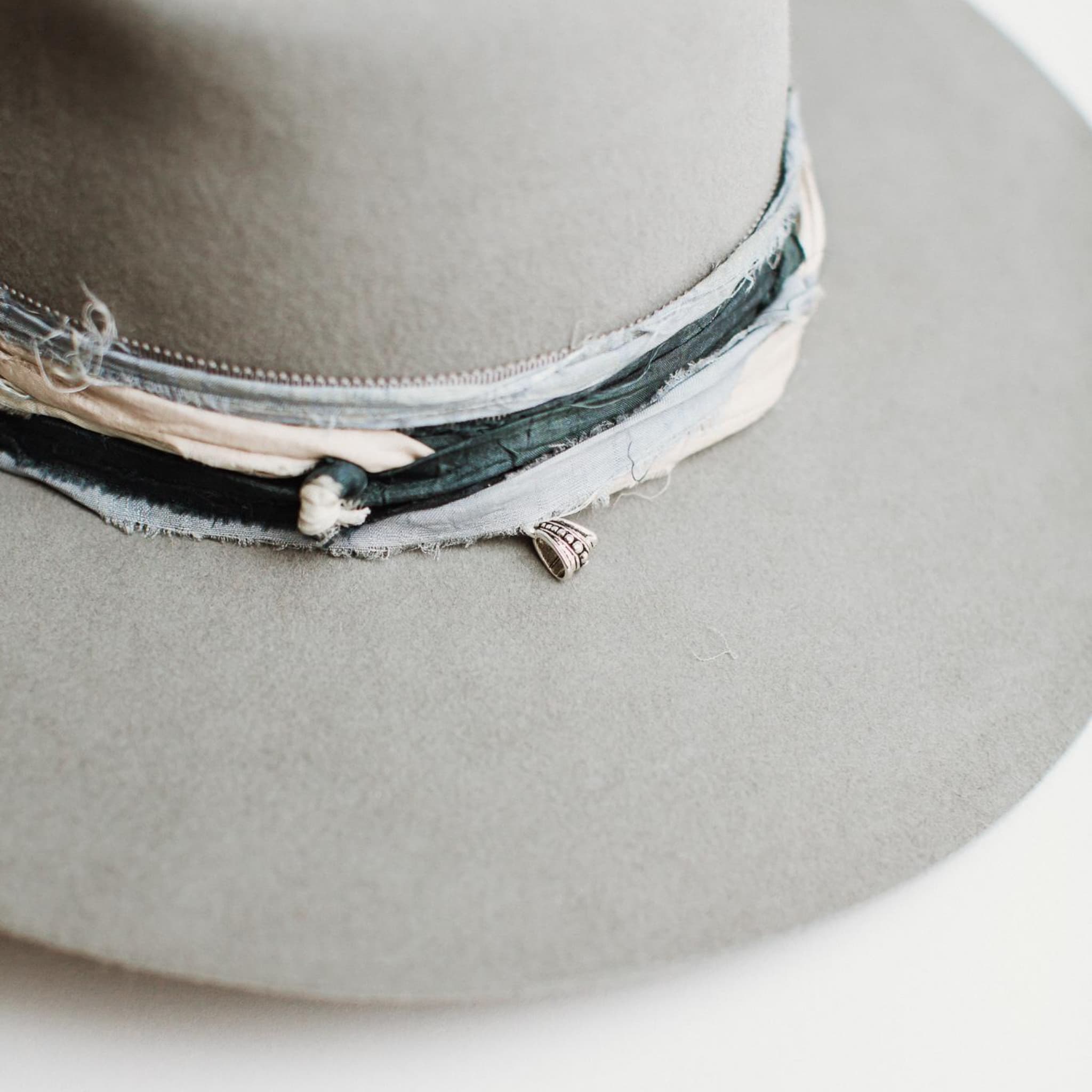 Close up detail of Santa Fe Winter felt hat by PHYLLi Designs showing sari silk trim and silver pendant charm.
