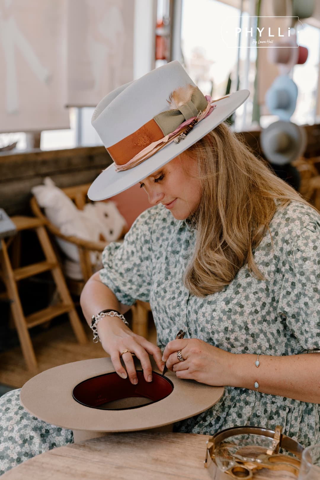 Laura Hall handcrafting a felt hat in the PHYLLi Designs studio wearing the Santa Monica crystal blue hat.