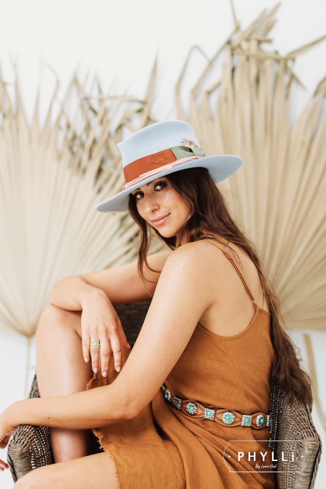 Woman wearing the Santa Monica crystal blue felt hat by PHYLLi Designs showing rust band and silk detail.