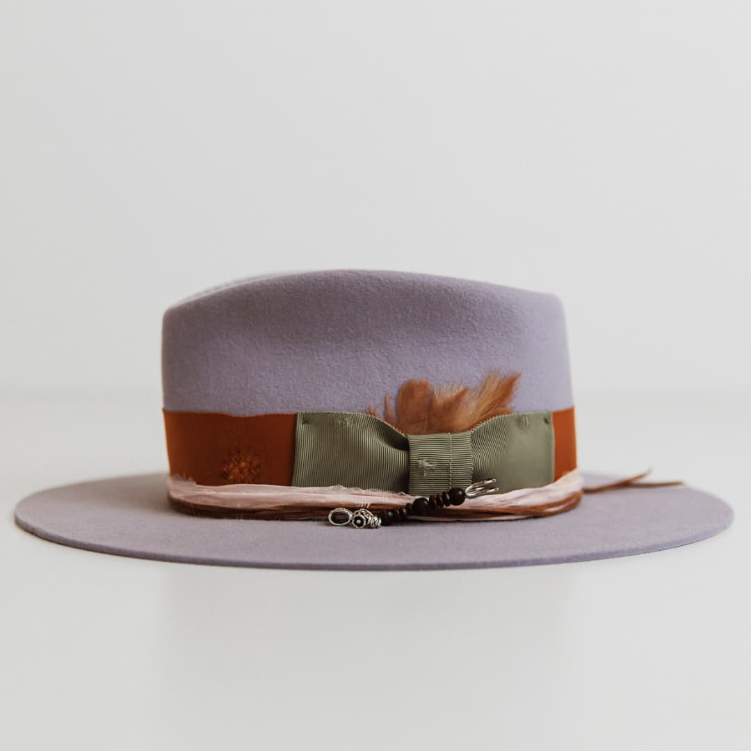 Left side view of Santa Monica Lilac felt hat by PHYLLi Designs with rust Japanese grosgrain band, oil green bow, sari silk trim and silver hat pin.