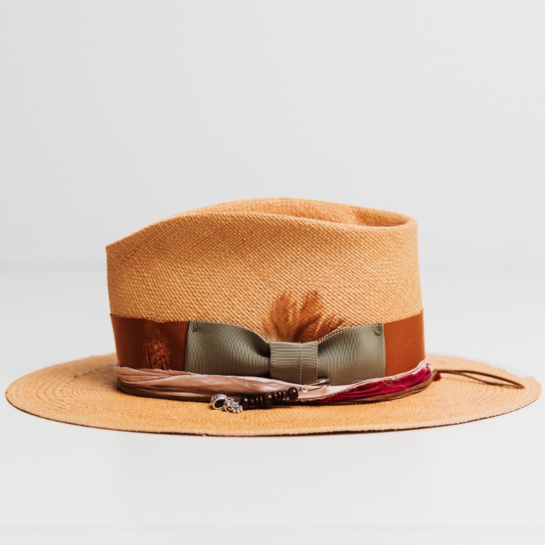 Side view of Santa Monica Panama hat featuring tan chicken feathers, oil green bow and Rust grosgrain band.