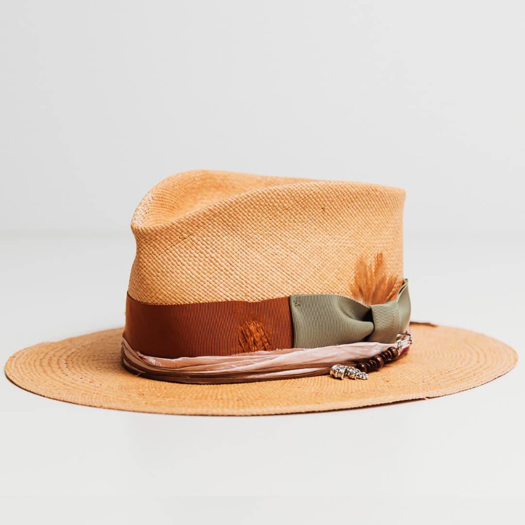Santa Monica Panama hat showing Rust grosgrain band, Oil Green bow, tan suede string and silver hat pin with wooden beads and charms.
