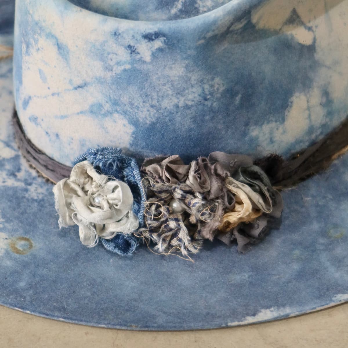 Close up detail of the Shibori Limited Edition felt hat showing sari silk lapel blooms with pearl centres.