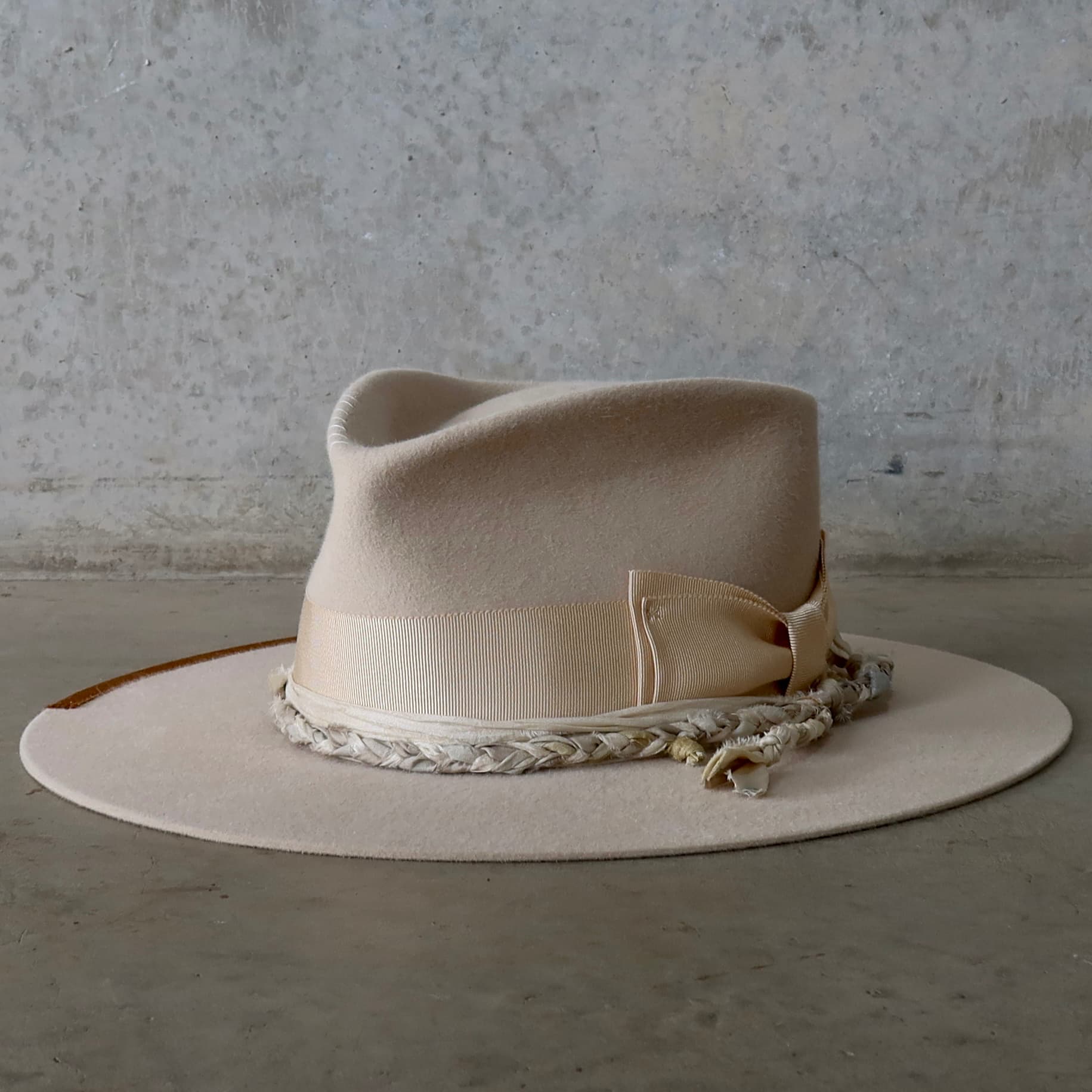 Front left angle of the beige felt hat Shoalhaven by PHYLLi Designs with sand grosgrain bow band and braided sari silk trim.