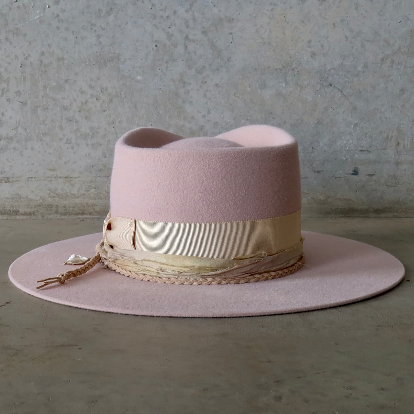 Back view of the baby pink felt hat Sorbet by PHYLLi Designs featuring plaited nude suede string with rough pearl pendant.
