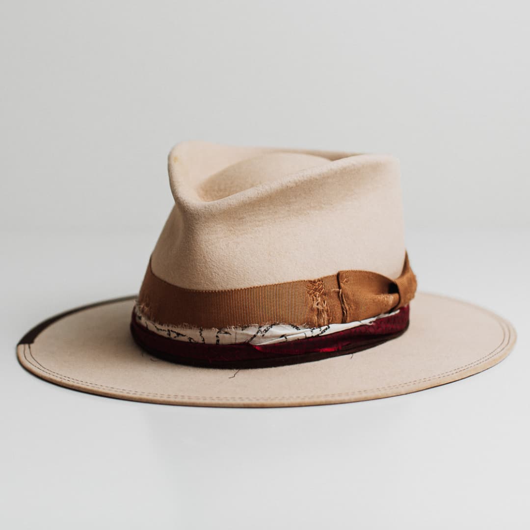 Front left angle of the Spice Alley beige felt hat by PHYLLi Designs with copper grosgrain band and layered crimson red sari silk trimming.