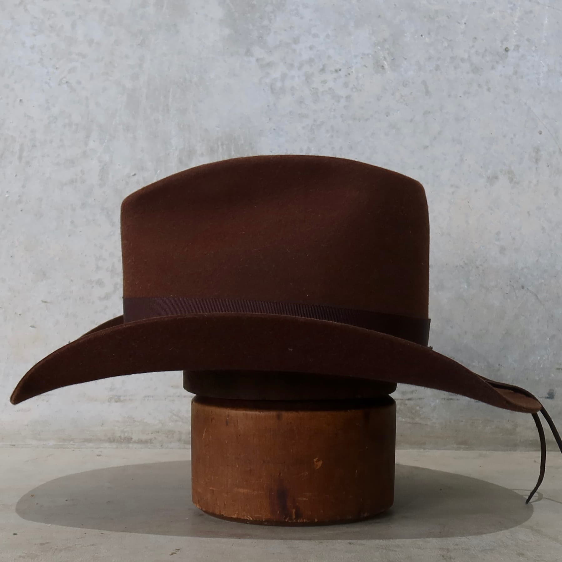 Left side view of the chocolate cowboy hat Spicer by PHYLLi Designs with chocolate grosgrain band and leather tie back.