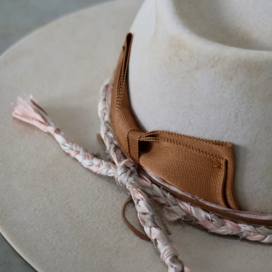 Close up detail of the Starlight felt hat showing the plaited sari silk trimming in nude and soft pink.