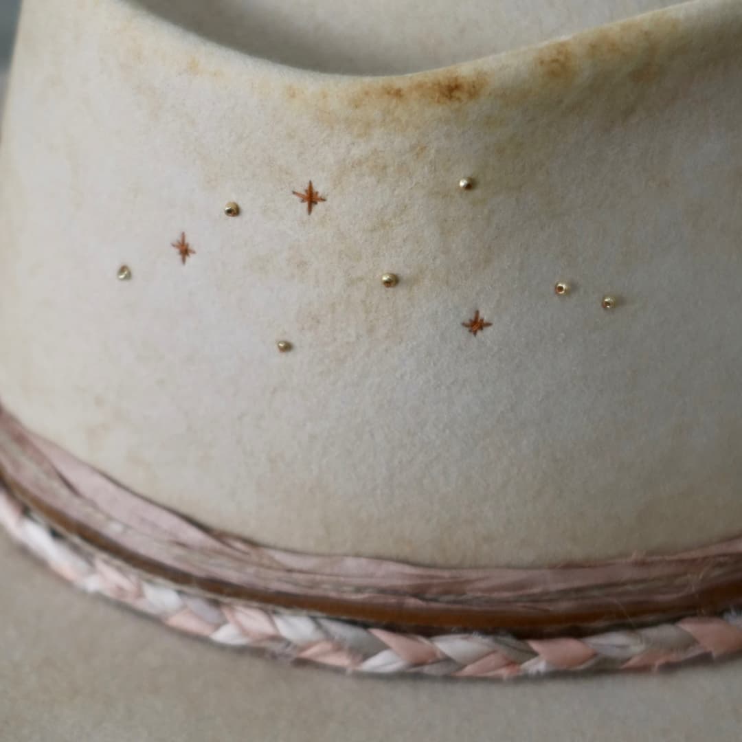 Close up detail of the Starlight felt hat showing the copper twinkle star embroidery with gold glass beads.