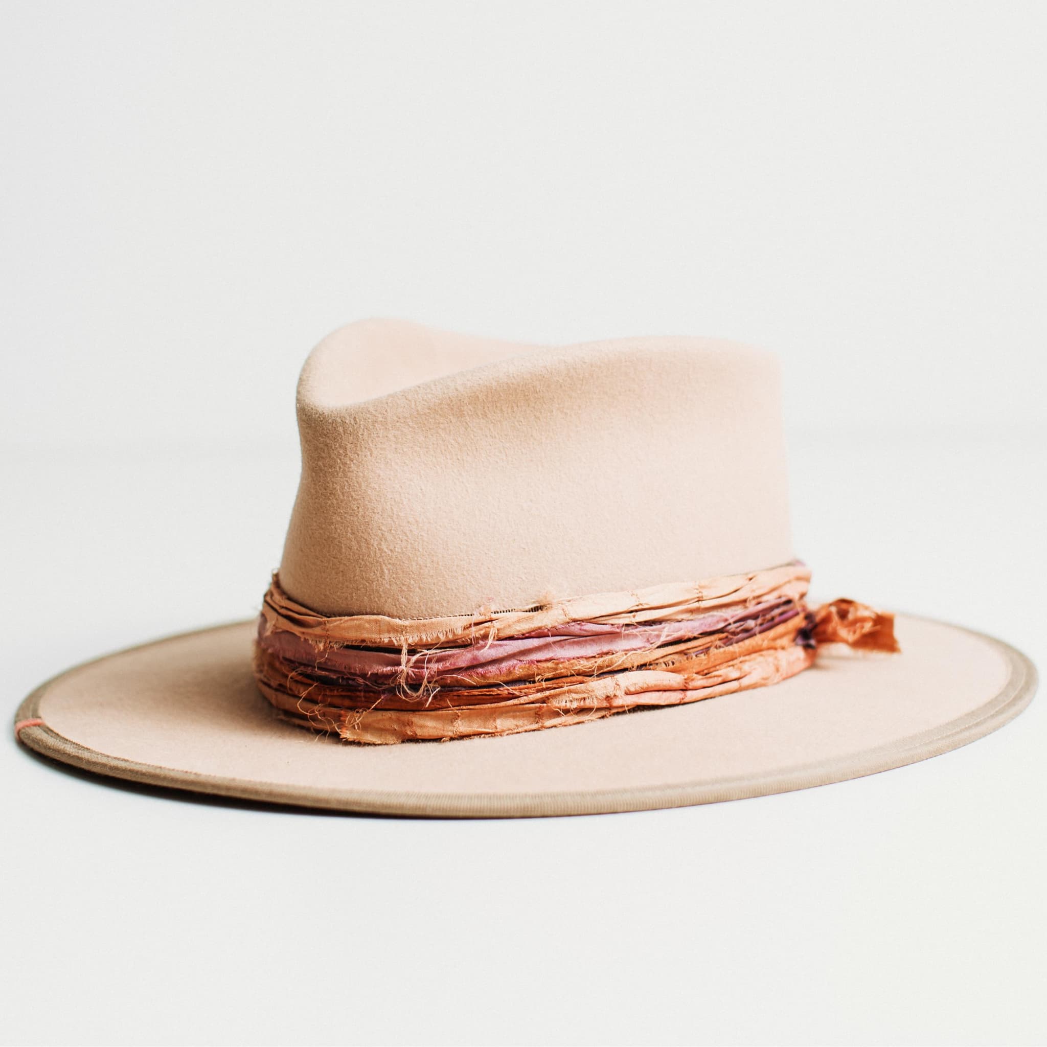 Front left angled view of Sunset sand felt hat with French grosgrain band and layered sari silk trim.
