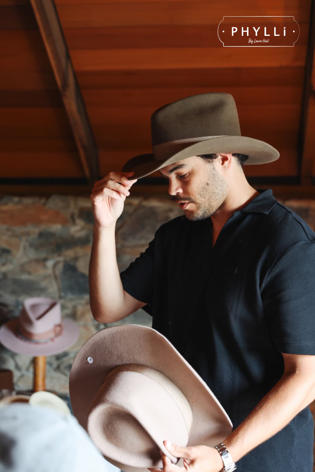 Man trying on a handcrafted western felt hat by PHYLLi Designs during the TCMF Wheeler hat bar experience.