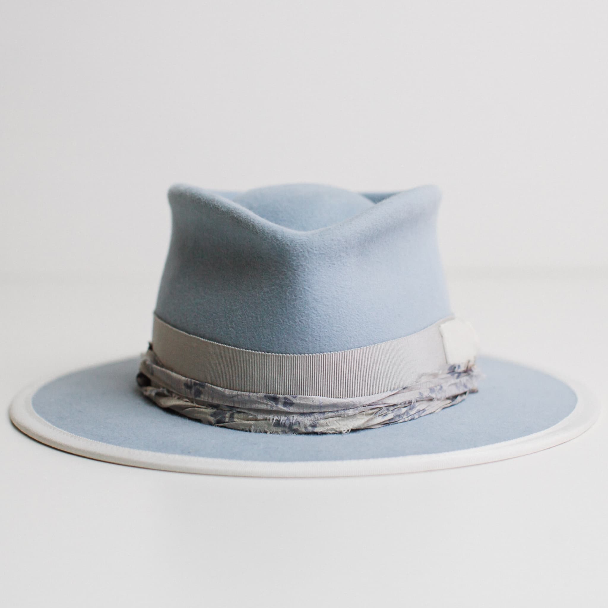 The Arrow crystal blue felt hat by PHYLLi Designs with dove Japanese grosgrain band, ivory velvet bow, ivory brim trim and dusty blue sari silk trim.