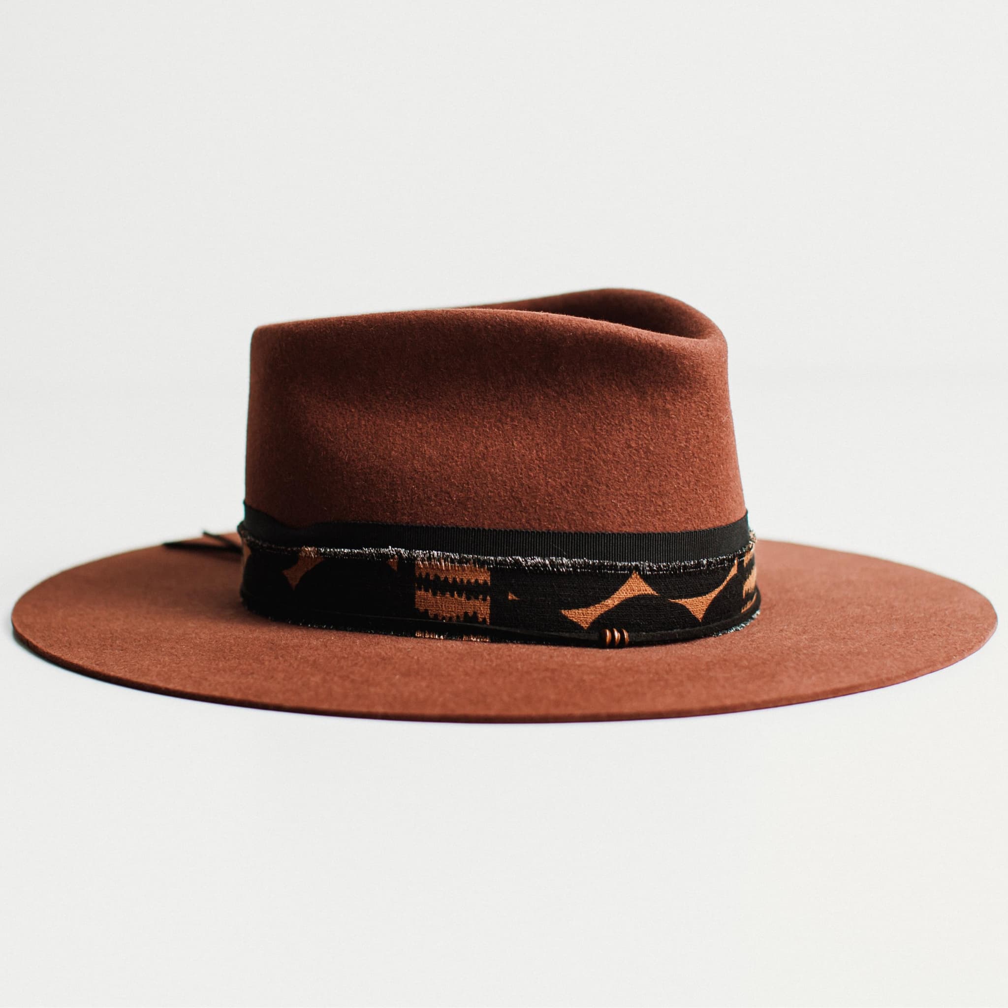 Angled view of russet wide-brim felt hat with decorative band by PHYLLi Designs.