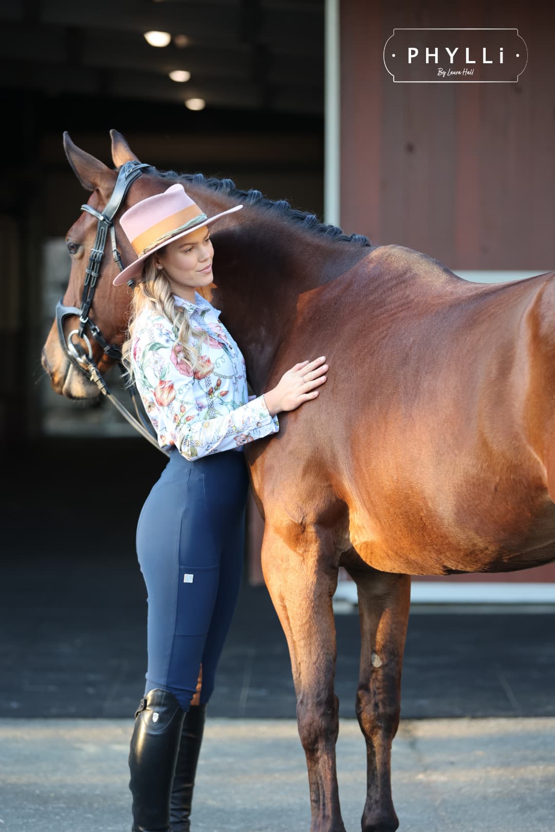 Woman wearing The Blush felt hat standing beside horse at stable.